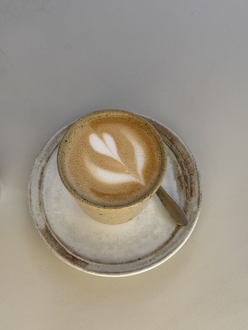 Flat white in a speckled ceramic cup on a pale surface