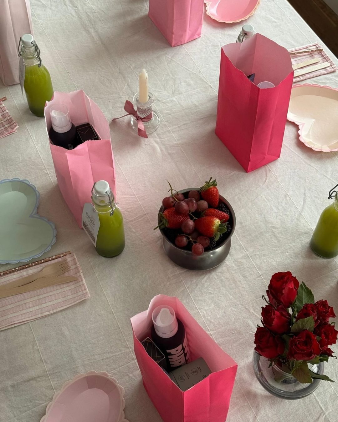 Overhead view of a styled table with pink favour bags, juices and roses