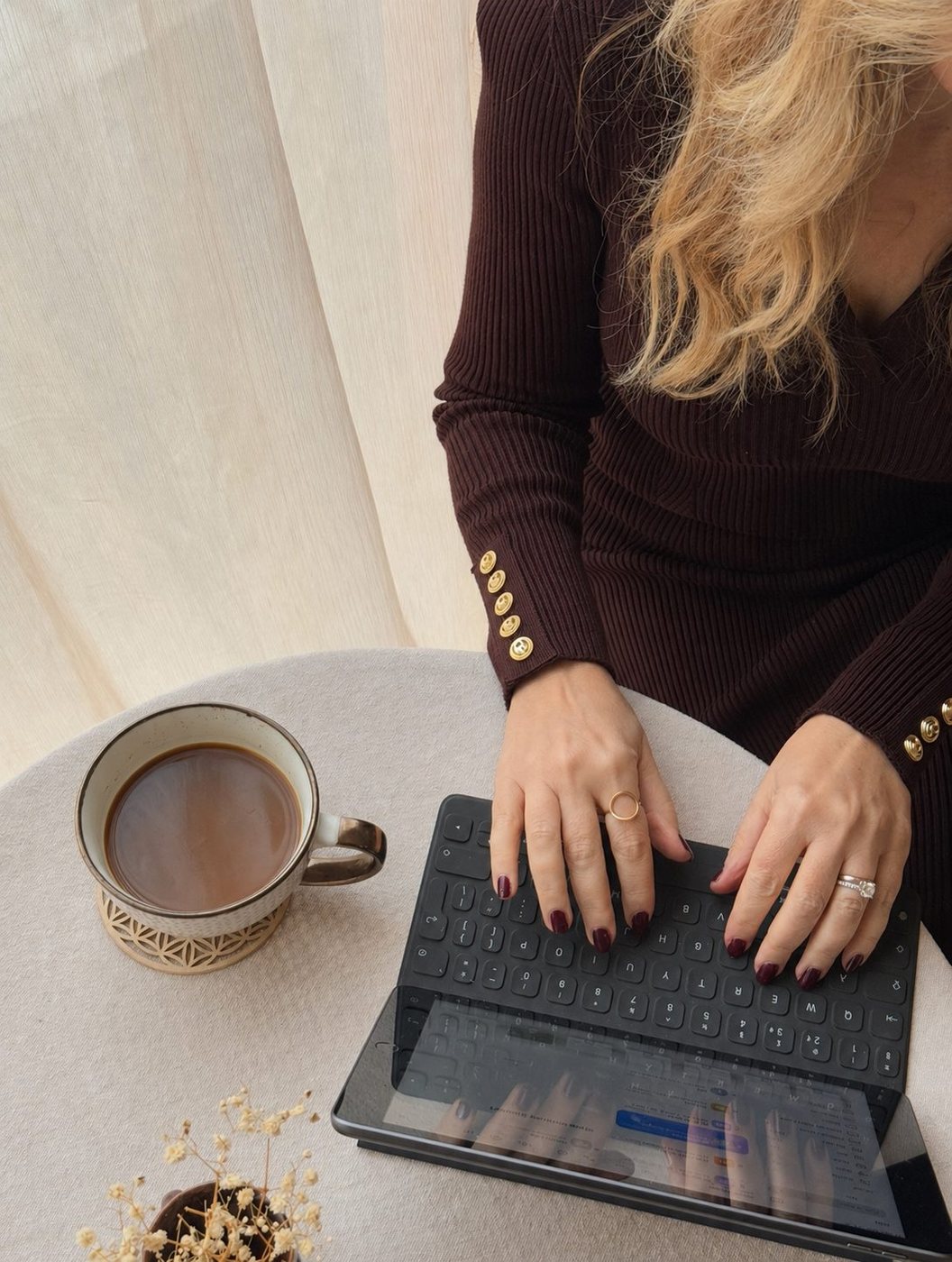 Hands typing on a tablet beside a coffee cup